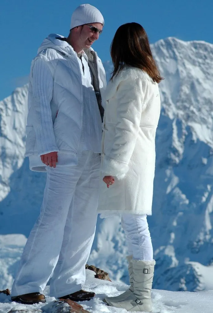 A couple in warm alpine layers on the snow at Liebig Dome, high in Aoraki / Mt Cook National Park