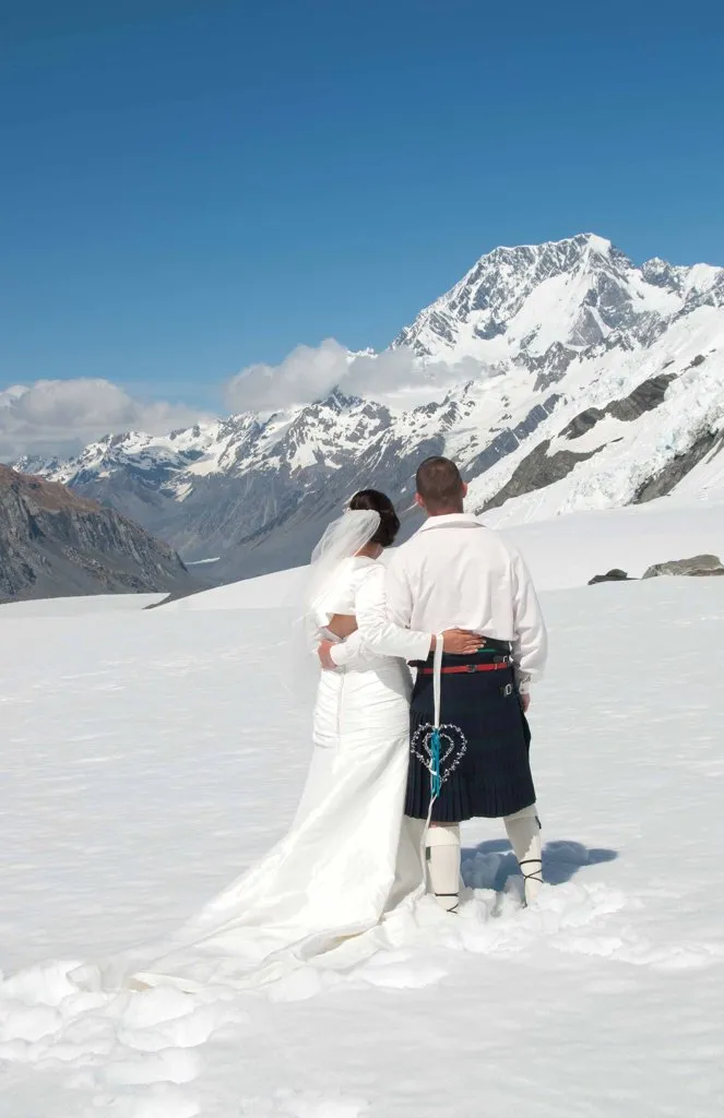 A bride and groom looking out to Aoraki / Mt Cook from the snow of Richardson Glacier